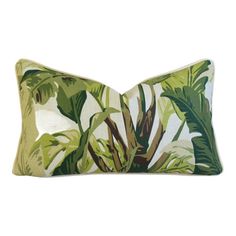 a green and white pillow with large leaves on the front, sitting on a white background