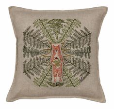 a decorative pillow with an embroidered fox and leaves design on the front, in beige linen