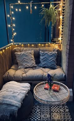 a couch and table in a room with string lights on the wall above it, next to a potted plant