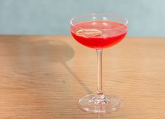 a close up of a wine glass on a table with a drink in the middle