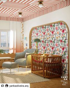 a baby's room with floral wallpaper and striped ceilinging, including a crib