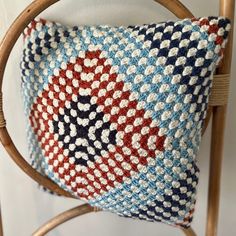 a crocheted pillow sitting on top of a wooden chair