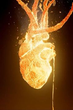 an orange and yellow heart shaped object floating in the air with fire coming out of it