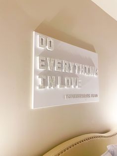 there is a light up sign that says do everything in love on the wall next to a bed