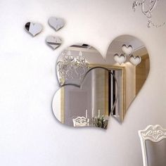 a heart shaped mirror hanging on the wall next to a table with chairs and a chandelier