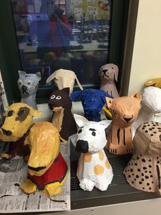 there are many paper mache animals sitting on the shelf in front of the window