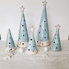 five ceramic christmas trees with star decorations on the top one is blue and white, while the other has black dots