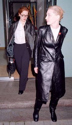 two women walking down the street in black leather jackets and pants, both wearing white shirts