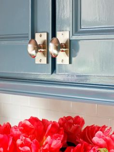 red tulips are sitting in front of the blue cabinet doors and handle handles