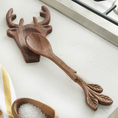 two wooden spoons sitting on top of a counter next to a bowl with sea salt in it