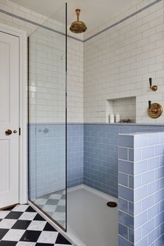 a bathroom with blue and white tiles on the floor, shower stall and sink area