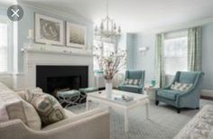 a living room filled with furniture and a fire place under a chandelier in front of a fireplace