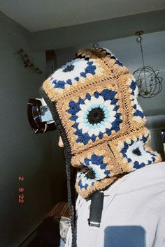 a person wearing a crocheted hat with a camera attached to the back of it