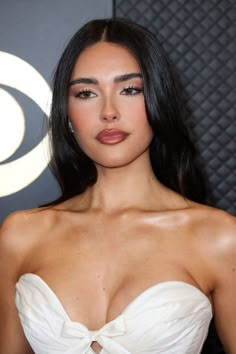 a woman with long black hair wearing a strapless white dress and posing for the camera