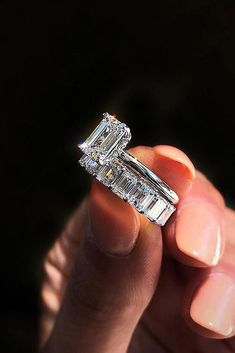 a woman's hand holding an engagement ring with two baguettes on it