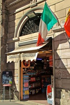 a store front with flags hanging from it's windows and an italian flag in the window