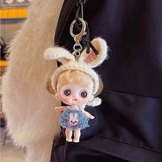 a little doll hanging from the side of a purse with a keychain attached to it