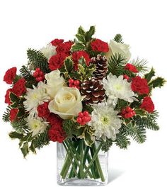 a bouquet of red and white flowers in a clear vase with pine cones on top