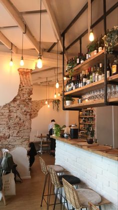 the interior of a restaurant with brick walls and exposed ceilings, bar stools, and shelves filled with liquor bottles