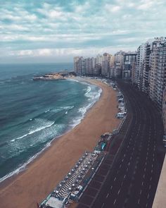 an aerial view of the beach and ocean with cars parked on the road next to it