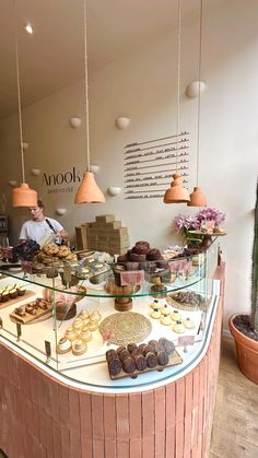 a pastry shop with an assortment of pastries on the counter and hanging lights above it