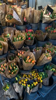 there are many bags full of tulips on the street market stand with flowers in them