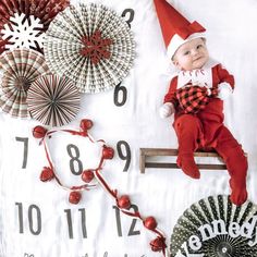 a baby dressed up as an elf laying on top of a table with paper fans