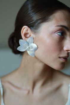 a close up of a person wearing earrings with flowers on it's ear and the top half of her face