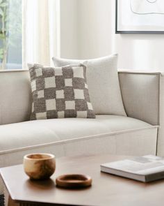 a white couch sitting next to a table with a book and vase on top of it