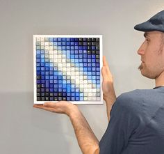 a man is holding up a blue and white mosaic tile