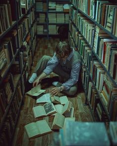 a man is sitting on the floor in a library with many books scattered around him