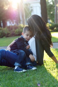 a mother and son are sitting on the grass