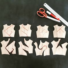 several pieces of paper cut out to look like vests with scissors next to them