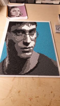 a man's face made out of legos on a wooden table next to other items