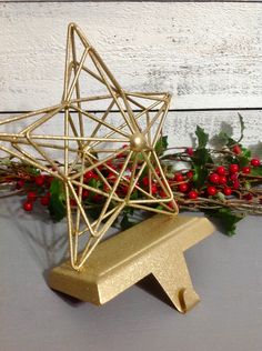 a gold ornament sitting on top of a table next to holly and berries