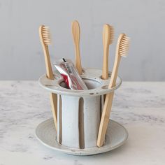 toothbrushes and dental floss in a cup on a marble countertop,