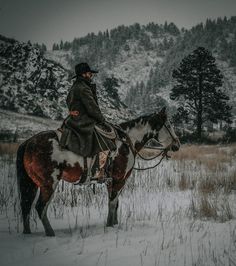 a man riding on the back of a brown and white horse in snow covered field