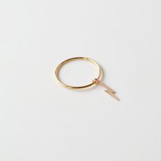 A lightning bolt charm dangles on a thin band ring. Can be worn as a midi or regular ring All 14K Gold Filled or Sterling Silver Made from 1mm full round wire. Gold Filled has 100 times more gold than gold plated jewelry. Gold filled wire is created by taking a sheet of 14 karat gold and bonding it through extreme heat and pressure to a core of semi-precious metal (brass). This is a very sophisticated process and only a few mills in the world do it. You should not mistake this process for gold p Lightning Bolt Ring, Bolt Ring, Sterling Silver Stacking Rings, Silver Stacking Rings, Extreme Heat, Charm Rings, Engraved Items, Precious Metal, Lightning Bolt