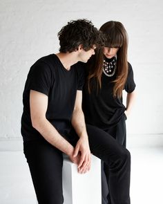 a man and woman are sitting on a white box together, looking at each other