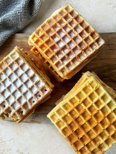 three waffles sitting on top of a wooden cutting board