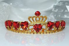 ♚ Crown Design ♚ This beautiful red heart crown is inspired by the Queen of Hearts hair and costume. ♚Material♚ Zinc alloy, red acrylic diamonds, rhinestones. ♚ Headpiece Size♚ 15.5cm L * 13.5cm W * 4.8cm H. Suitable for girls, women to wear, suitable for most people's headdress. ♚ Widely Applicable Occasions♚ Sparkling rhinestone tiara is perfect for any party, create a stunning sparkling tiara for your very special day, add fun to your party and make sure you catch everyone's attention. ♚ Comfortable to wear ♚This crown is just like a regular tiara without a hair comb, making it more comfortable for you to wear! Red And Gold Crown Quinceanera, Queen Of Hearts Hair, Quince Crowns Red And Gold, Gold And Ruby Crown, Red Heart Crown, Queen Of Hearts Crown, Queen Of Hearts Gold Crown, Gold Crown With Red Jewels, Quinceanera Crown