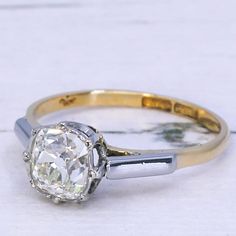 an engagement ring with a diamond in the center and two tone gold band around it