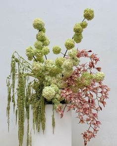 a white vase filled with lots of green and pink flowers