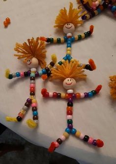 several colorful beaded dolls sitting on top of a white cloth covered table next to each other