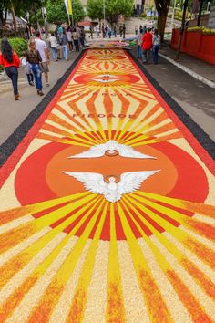 people walking down the sidewalk with an artistic design painted on it's side in orange and yellow