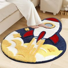 a person sitting on a bed with a rug in the shape of a rocket ship