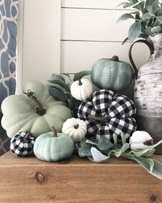 some pumpkins and gourds are sitting on a wooden shelf next to a vase