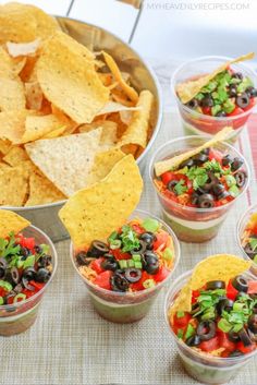 several cups filled with different types of food and chips on top of a tablecloth