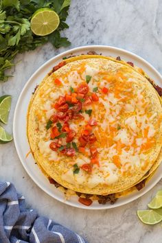 an omelet on a plate with limes and cilantro next to it