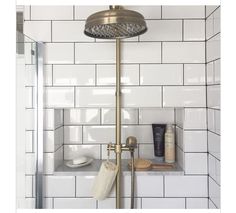 a shower head and hand held shower faucet in a white tiled bathroom with gold fixtures